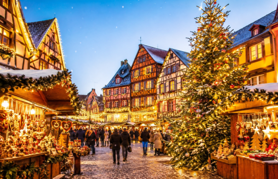 Chalets décorés et grand sapin illuminé dans un village alsacien aux maisons à colombages.