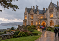 Château d’Abbadia éclairé sous une pluie fine, avec des visiteurs munis de parapluies à Hendaye.