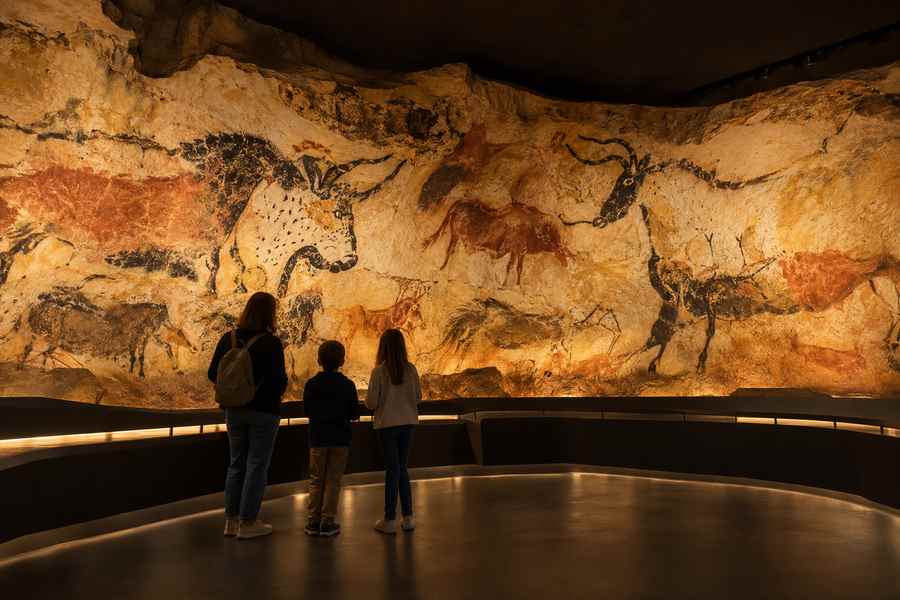 Famille observant une reproduction d’art pariétal dans une galerie d’interprétation.