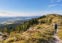 Randonneuse sur un sentier du Crêt Pela au-dessus des forêts du Jura