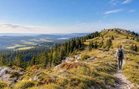 Randonneuse sur un sentier du Crêt Pela au-dessus des forêts du Jura
